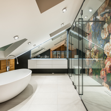 Modern attic wetroom with freestanding tub and floral wall design.