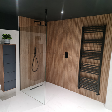 Modern wetroom with glass shower panel and wooden wall accents.