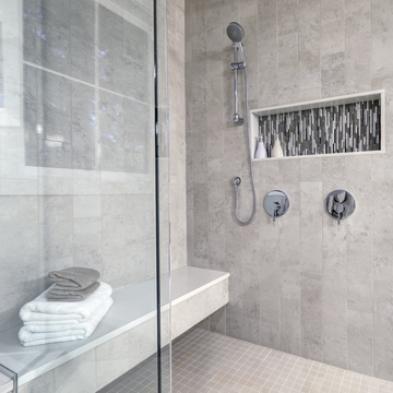 Modern wet room with sleek shower, built-in shelf, and tiled walls.