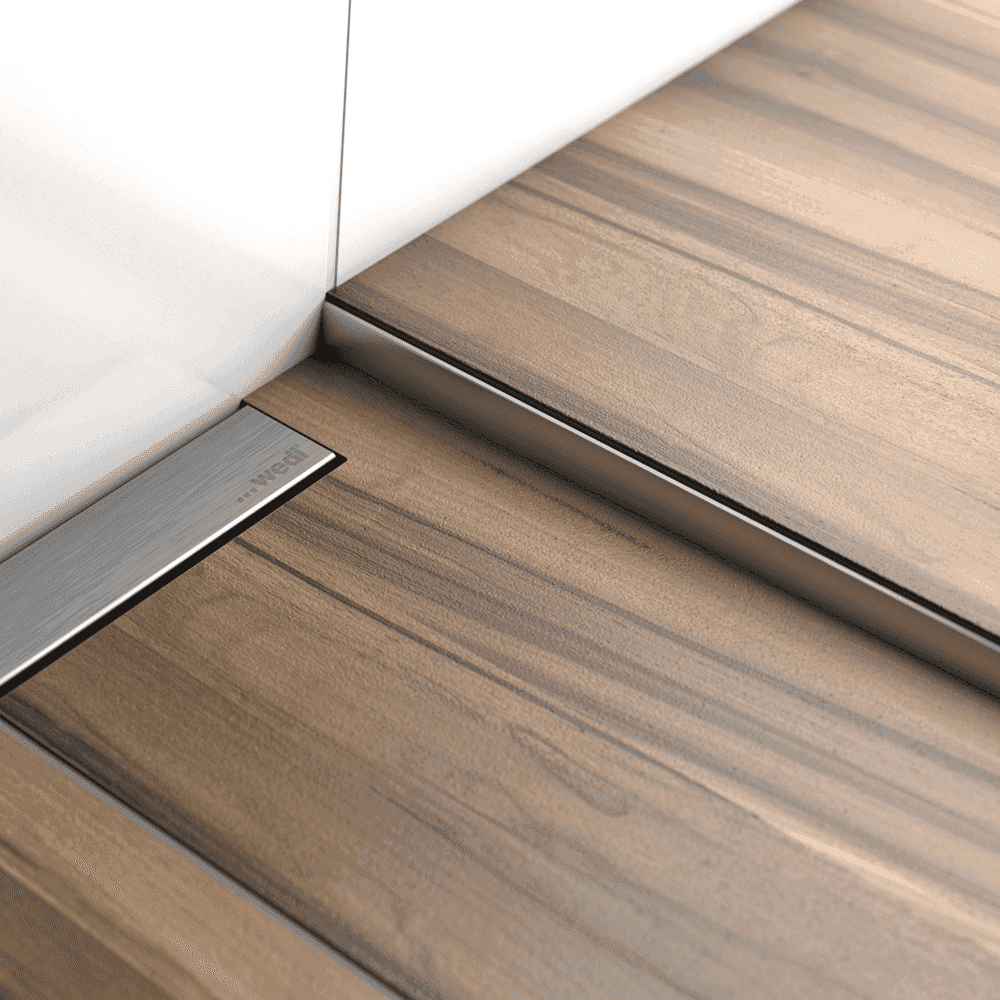 Installed Side Slope Tile Profile for WetBase® One Infinity by wedi: 1200mm shown in a modern wet room with wood-effect tiles for a clean finish.